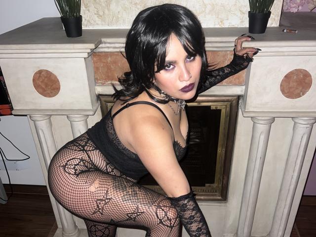 SilenaLee with black lace lingerie, fishnet pattern, dark makeup, and a nose ring, leaning on a fireplace, showing her ass and small tits, with black gloves.