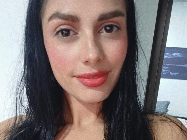 AnaisHilton has dark wet black hair, pinkish-red lips, brown eyes, and a slight smile. She's looking at the camera with a soft, relaxed expression.