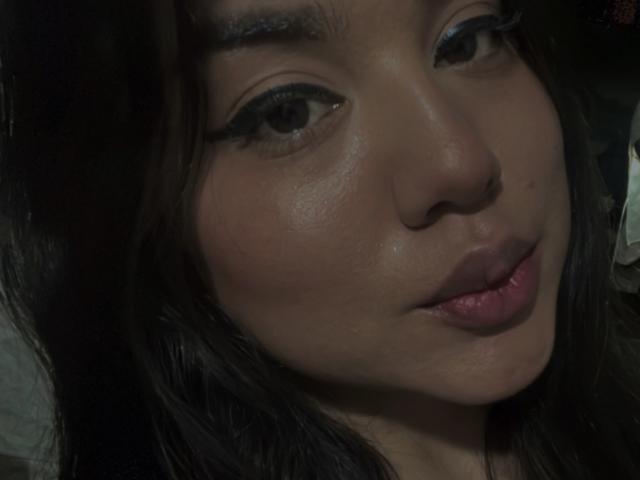 SteffanyTaylor's face, showing dark eyebrows, black eyeliner, shiny skin, and pink lips, with her head slightly tilted to the side, dark hair partially visible.