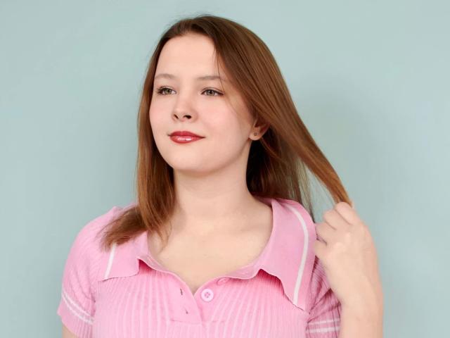 ClaireLips-hot with light brown hair, pink striped polo, holding her hair, smiling with red lipstick, fair skin, blue-green background, upper body shot.
