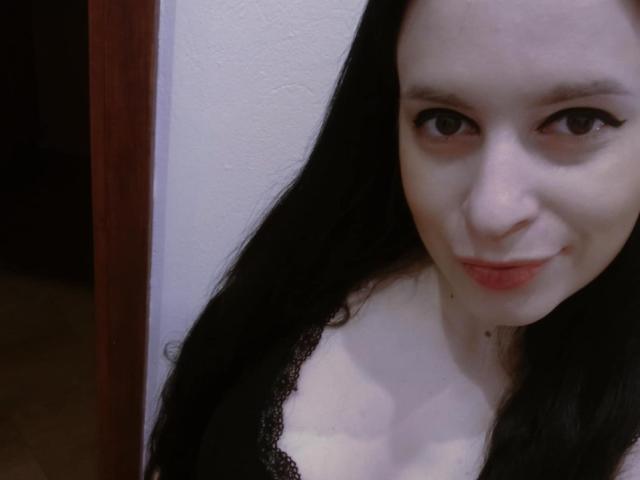 ScarlettAmore a la peau pâle, de longs cheveux noirs et un sourire discret. Elle porte un haut en dentelle noire qui révèle ses petites seins. Ses yeux marrons sont légèrement en amande..