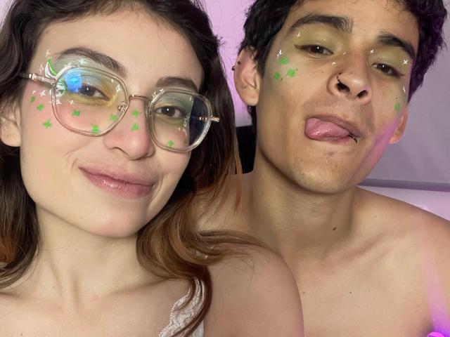 CamilleLiam with glasses and green glitter on face, next to shirtless Liam with green glitter and tongue out, both smiling. Liam's nose is pierced. CamilleLiam has light skin.