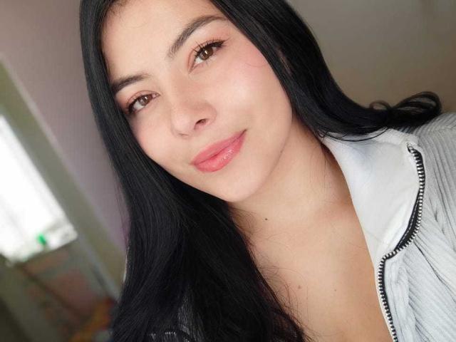 SophiaRamirez has long black hair, brown eyes, pink lips, and is wearing a gray zip-up jacket. Her face is slightly tilted to the right with a subtle smile.