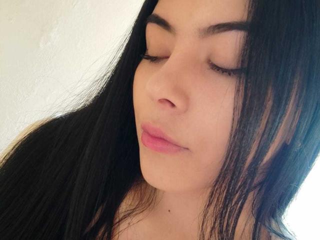 SophiaRamirez with closed eyes, long black hair, and pink lips, looking down. Her face is centered, showing her smooth, light skin and subtle makeup.