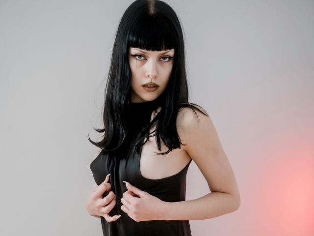 Riverly heeft zwart, steil haar met een pony, draagt een zwart topje zonder mouwen, waardoor haar kleine borsten zichtbaar zijn, waarbij ze haar tepels bedekt met haar handen, en heeft donkere, opvallende make-up..
