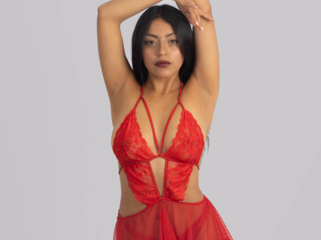Xewaa with long black hair, red lace lingerie, arms raised, exposing her tits and armpits, looking at the camera with a slight smile, light skin, sexy, confident.