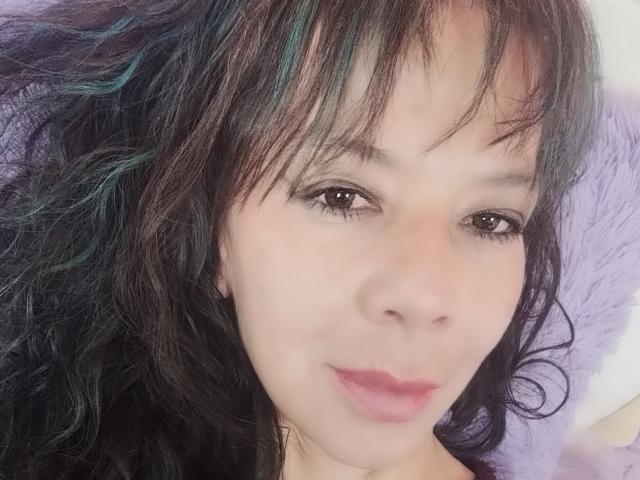 SamaraBellet ha i capelli scuri e ondulati con riflessi verde acqua, occhi marroni e labbra rosa, e guarda la fotocamera con un leggero sorriso. Ha una carnagione chiara..