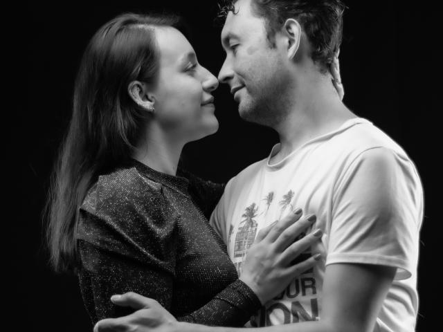 Jeremmy en Stacy kussen, met gesloten ogen. Jeremmy's hand rust op Stacy's borst, Stacy's hand op Jeremmy's borst. Ze glimlachen beiden zachtjes. Zwart-wit, intiem. Stacy draagt een sprankelend top..