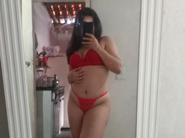 MariX69 in red lingerie, covering her tits with one hand, showing her ass and pussy in a mirror selfie. She has long dark hair, holding a phone.