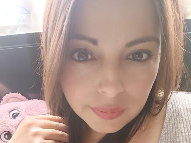 Seher has a cute face with brown eyes, light skin, and brown hair, smiling slightly with pink lips. Her hand is near a pink teddy bear.