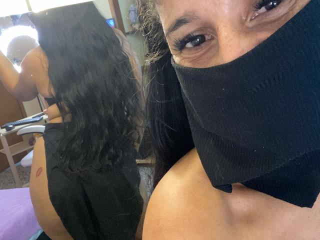 KiraTaleb mit langem, schwarzem Haar, einer schwarzen Maske und schwarzer Unterwäsche, die in einem Selfie ihr nacktes Gesäß zeigt und einen roten Lippenstiftabdruck auf ihrer rechten Gesäßwange enthüllt..