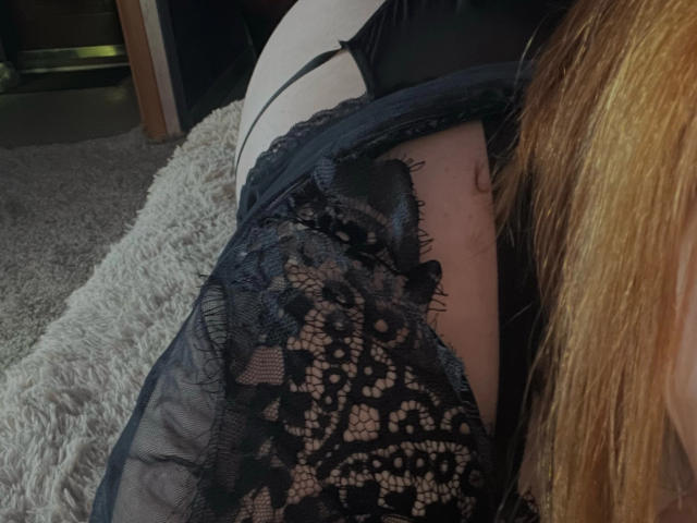 Il sedere di Mable Jocelyn, in biancheria intima di pizzo nero, è sdraiato su un morbido tappeto grigio, con i suoi capelli biondi a destra. Si notano il disegno del pizzo e un piccolo tatuaggio sul suo sedere..