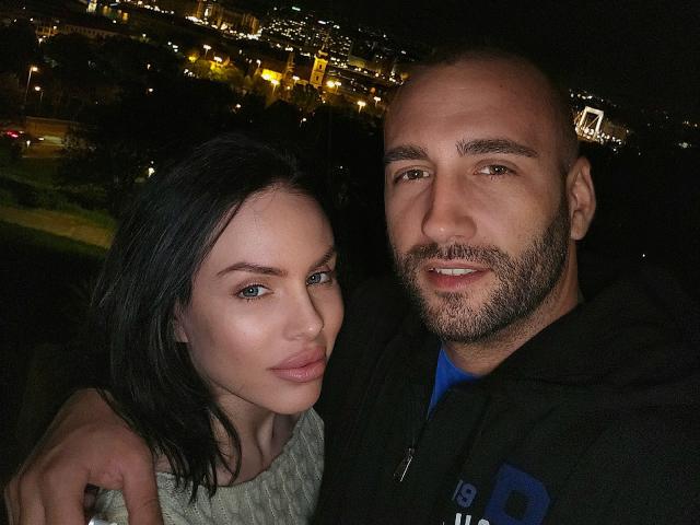 AxelCroftAndFordFairlane has a bald head with a beard, wearing a black hoodie, standing next to FordFairlane with black hair, blue eyes, and a grey sweater.