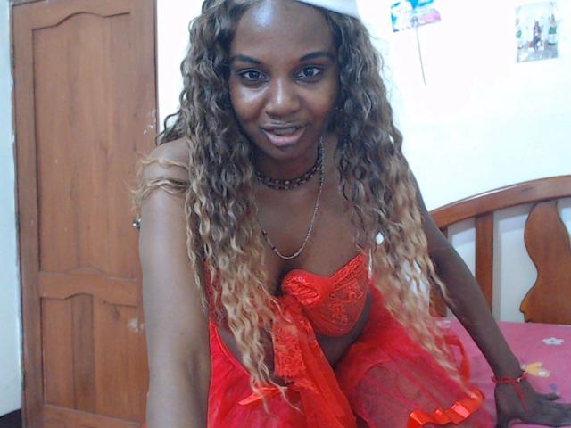 Katrhina87-hot with long, curly blonde hair, wearing a red lace bra and sheer red skirt, smiling, looking at the camera, showing her tits, in a wooden room.