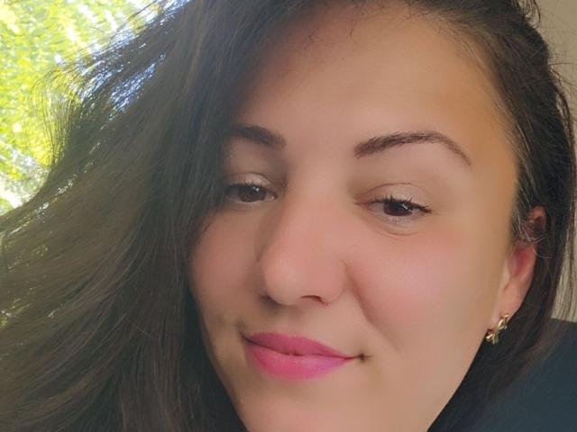 AmelyBrown has a cute face with light brown skin, dark brown hair, pink lipstick, small nose, and gold earrings, smiling slightly with eyes half-open.
