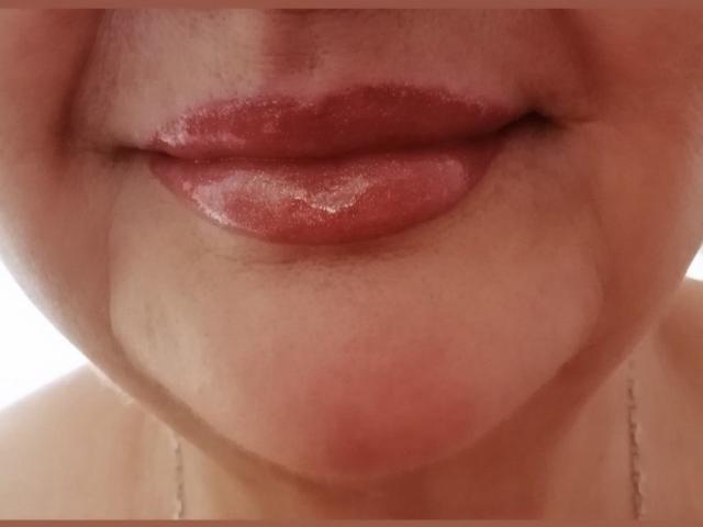 PeggySoft's shiny red lips are slightly parted, showing a subtle hint of her upper teeth. Her light skin has a few small, faint wrinkles around her mouth.