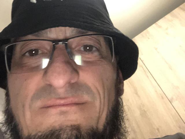 BernardFunny with a black bucket hat, glasses, and a beard, showing a serious, slightly goofy face. His nose is big and boogers are visible.