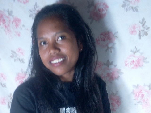 KattyMiriam has dark skin, long black hair, and is smiling with white teeth. She's wearing a black shirt and has small earrings. Her ass is not visible.