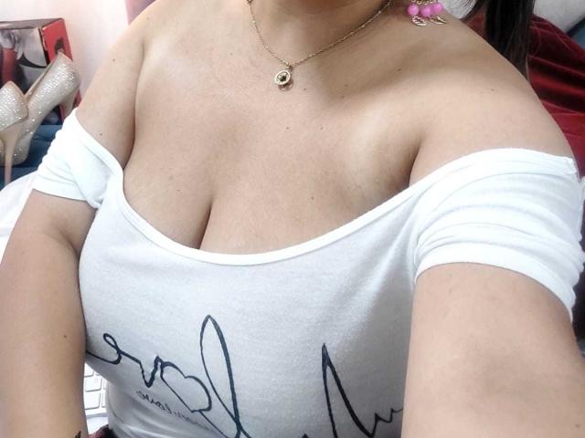 VictoriaKoad's tits are showing in a white off-shoulder top, with a gold necklace and her cleavage is prominent. Her skin is light and she has a small, round pendant.