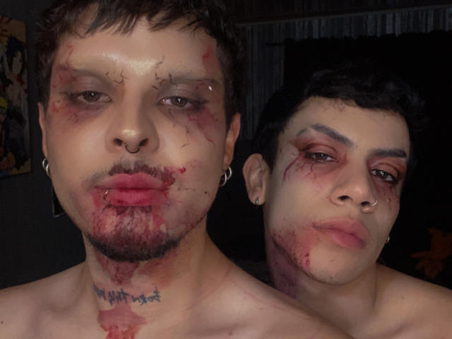 AronJames with bloody faces, puffy lips, and tattoos, standing shirtless. AronJames has short brown hair, nose ring, and earrings, while the other AronJames has darker hair and a nose ring.