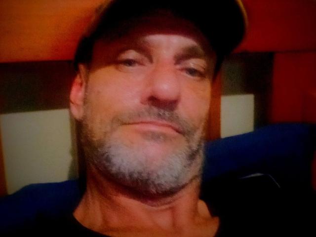 CunningStunts69 has a graying beard, slightly squinting eyes, and is wearing a black cap with a relaxed, confident expression. His nose is small and his skin is tan.