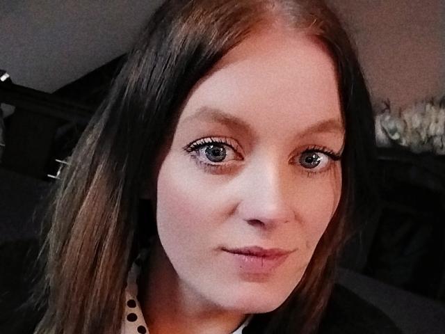 DollySoumise69 has pale skin, brown eyes, and medium-length brown hair, with subtle makeup and a small smile. Her boobs are not visible in this image.
