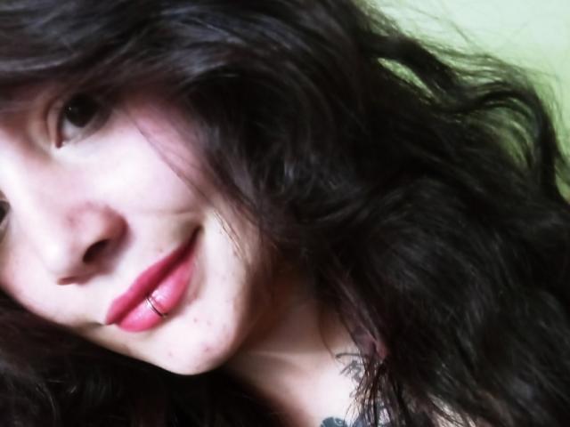 SweetAmeliee hat langes, welliges, schwarzes Haar, blasse Haut und ein leichtes Lächeln mit rosafarbenen Lippen und einem Lippenpiercing. Ihre Nase ist klein, und sie hat ein paar Sommersprossen..