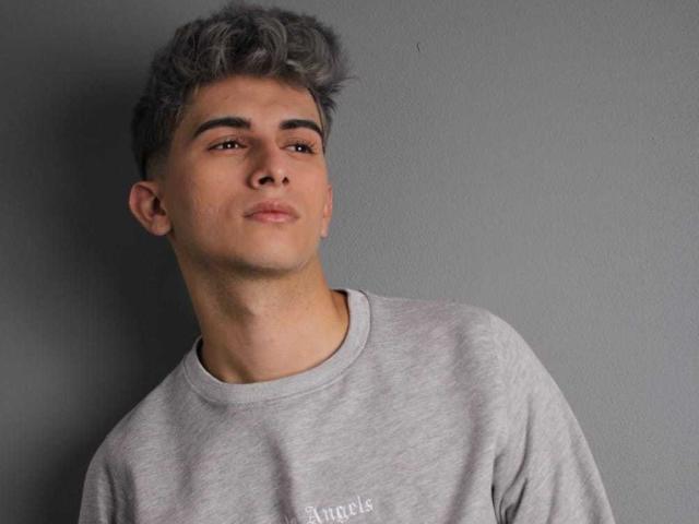 CandyEngel with grey curly hair, brown eyes, and a light grey sweatshirt, looking slightly up with a neutral expression.