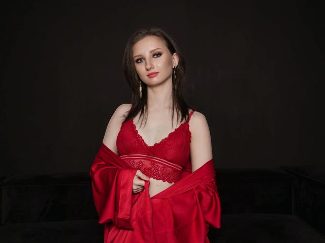 FlawLessLife with pale skin, blue eyes, and brown hair, wearing red lace lingerie and a matching silk robe, holding it off her shoulders, showing her tits.