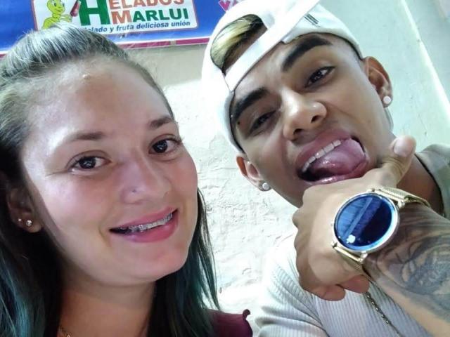 ParejaEnLlamas with a cute girl, she's got small tits and a big smile, and he's sticking his tongue out, showing off a gold watch with a blue face.