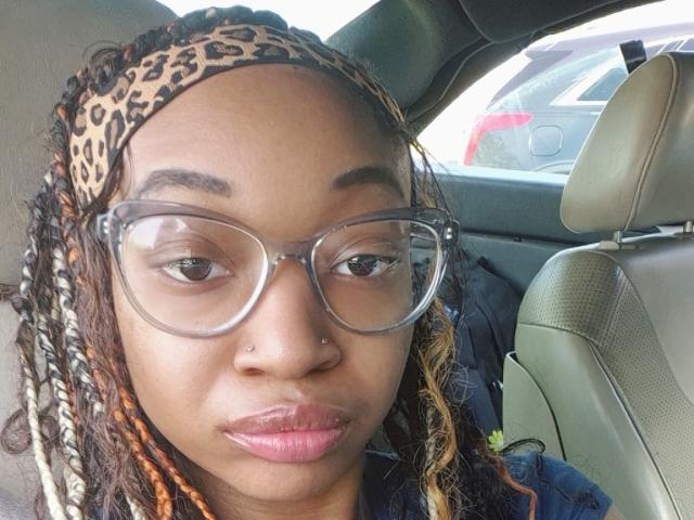 NadiaaSexy has a cute face with large glasses, a leopard headscarf, braided hair, and a nose ring. Her lips are slightly puckered. She's in a car.