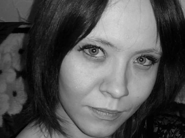 Black-and-white selfie of PinkMartines with medium-length dark hair, large eyes, and subtle makeup. Her face is centered, showing a slightly serious expression and natural skin texture.