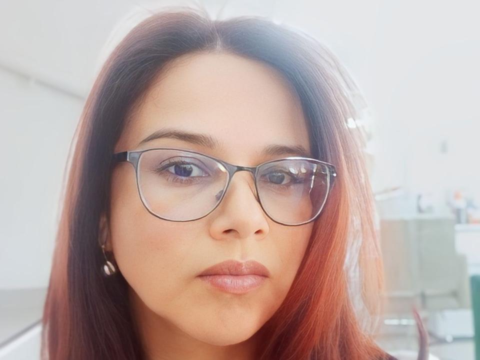 Marghotd with red-brown hair, wearing black glasses, has a pouty face, light skin, and glossy pink lips. Her tits are covered by her hair, and she's looking straight at the camera.