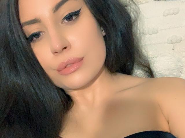 CellineStarX hat langes, schwarzes Haar, dicke Augenbrauen, schwarzen Eyeliner, glänzlich rosafarbene Lippen und einen hellen Hautton. Ihre nackten Schultern sind sichtbar, und sie trägt einen schwarzen Träger..