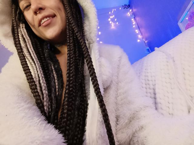 UrLadyXREM-hot with red lipstick, dark eyebrows, and long black hair, looking at the camera with a slight smile, wearing a black strap top, has light skin.