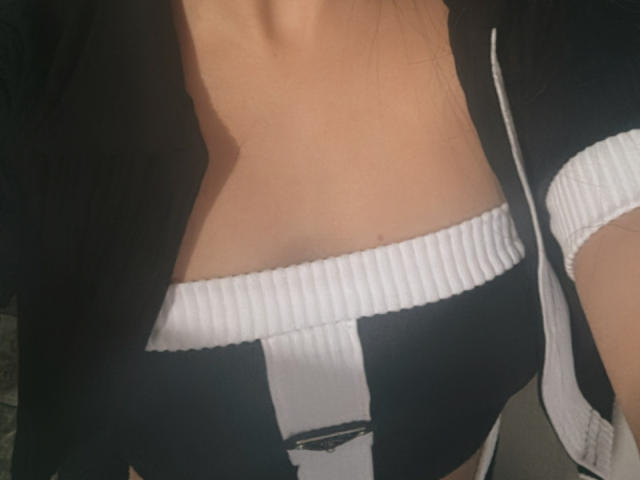 SarahGood's tits in a black and white ribbed sports bra with a zipper jacket. Her tan skin is visible, and the focus is on her chest.