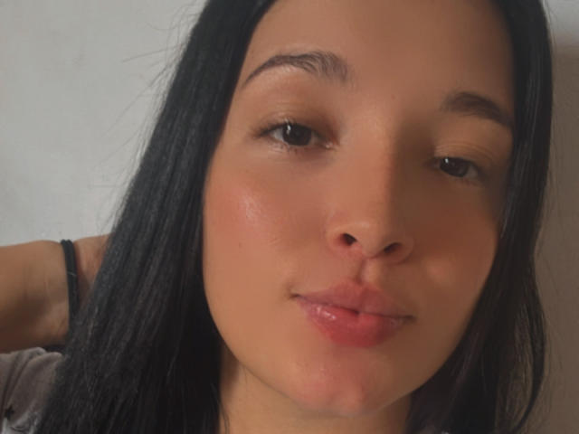 SarahGood's face, showing her cute nose, slightly parted pink lips, and long black hair. She has brown eyes, a light tan skin tone, and a subtle smile.