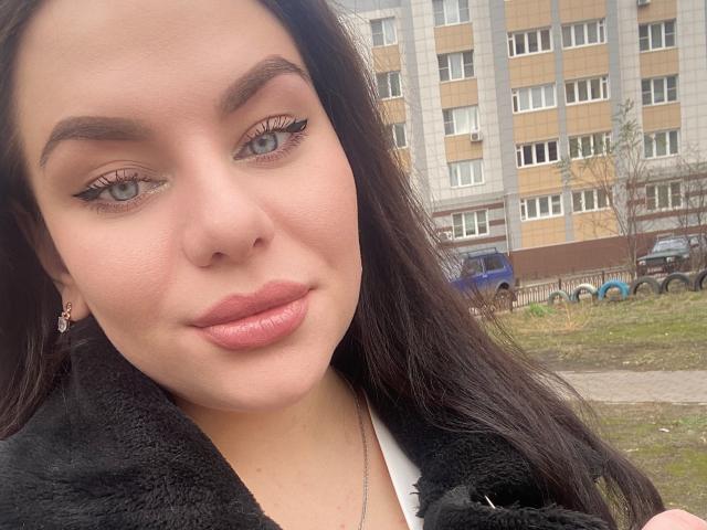 Dolci hat volle Lippen, dunkles Haar und trägt einen schwarzen, flauschigen Mantel. Sie hat ein süßes Gesicht mit dicken Augenbrauen und Eyeliner, und ihre Brüste sind nicht sichtbar..