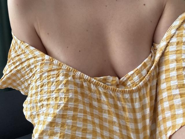 EricaLust's yellow and white checkered off-shoulder top, partially pulled down, exposing her pale skin and small, perky tits with a few dark moles.
