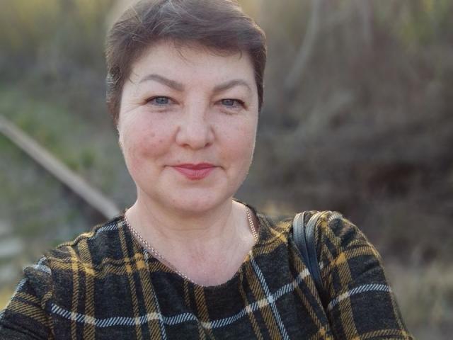 Elizabeth Wind a les cheveux courts et bruns, une peau claire et du rouge à lèvres. Elle porte une chemise à carreaux et affiche un léger sourire, avec un regard subtil et confiant. Ses seins sont petits..