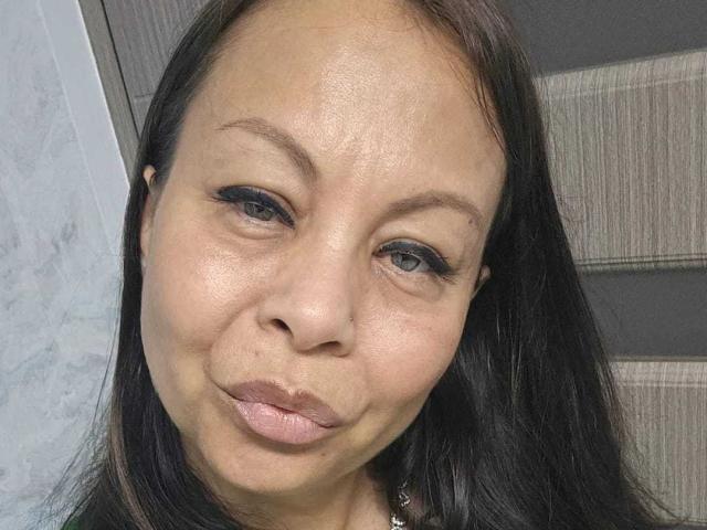 ColetteBlanche has medium brown skin, black straight hair, and is making a pouty face with her pink lips. She has a nose piercing and black eyeliner.