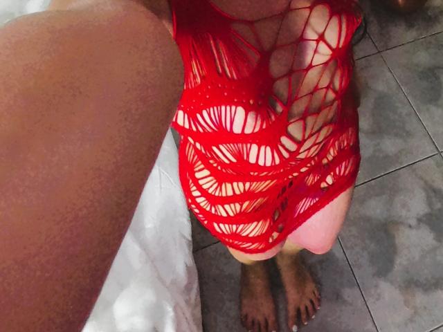 NatashaSteven's red, fishnet-style dress with large, circular, open-weave patterns, exposing her bare tits and part of her pussy. Her brown, hairy arm is on the left.