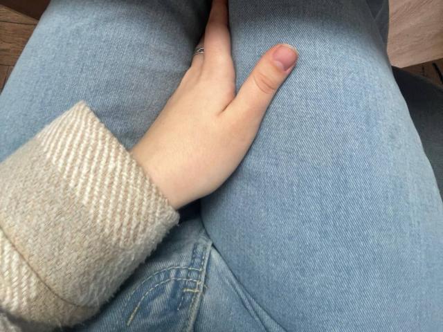 LaPulia's hand rests on her blue jeans, showing a ring on her finger, with her pinky slightly raised, wearing a beige rib-knit sweater.