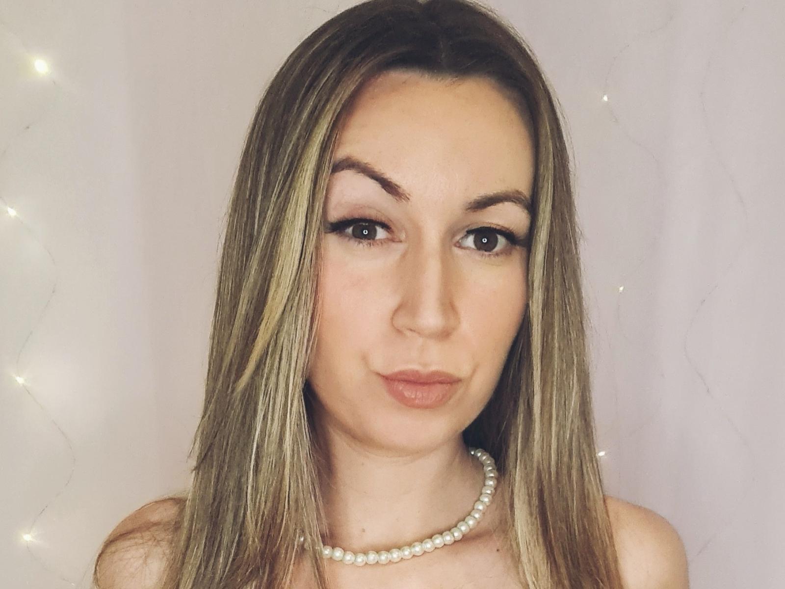 PipaDeGarance has long brown hair, brown eyes, and wears a pearl necklace. She's puckering her lips in a selfie with subtle eyeliner and a cute, confident expression.