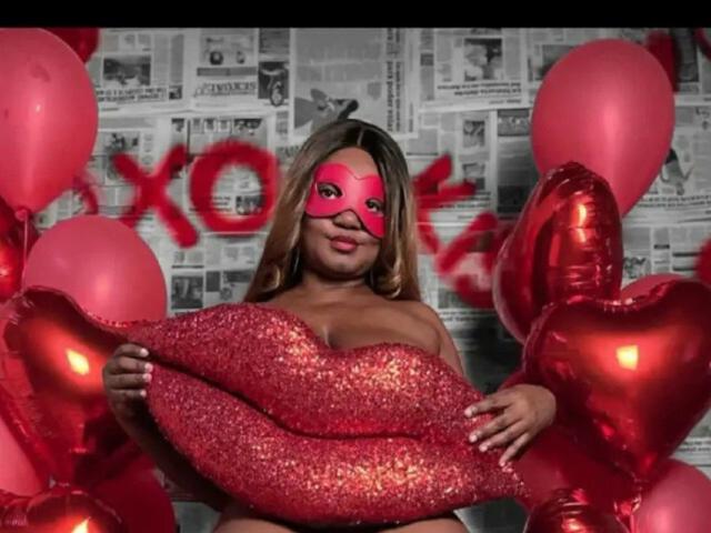 SweetBusty with red glitter lips mask, holding glittery red lips, surrounded by red balloons and heart-shaped balloons, wearing nothing, smiling, blonde hair, pink lipstick.
