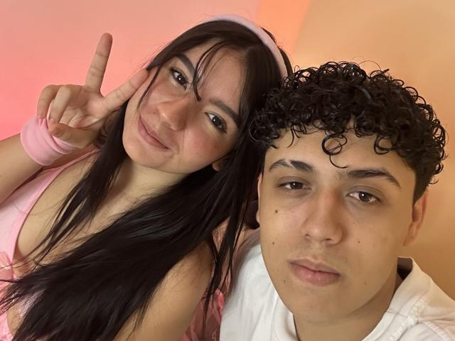 WelcomeToSky with long black hair and pink headband makes a peace sign next to WelcomeToSky with curly black hair and white shirt, both smiling.