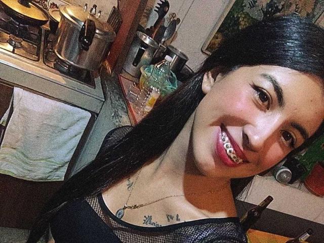TifanyTobon ha lunghi capelli neri, occhi marroni e un sorriso carino che mostra i denti. Indossa una maglietta nera in rete e i suoi piccoli seni sono leggermente visibili..