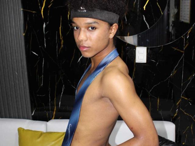 LiamMiranda with a dark headband, wearing a blue tie that's hanging open, exposing a slim, smooth, brown-skinned chest and a small, flat ass. Dark curly hair.
