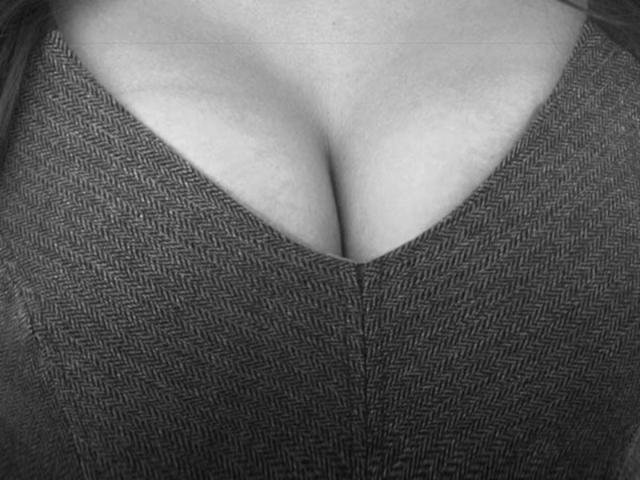 PaolaH's tits, showing a cleavage with a dark, zigzag-patterned, V-neck top. The image is a black-and-white, close-up shot.