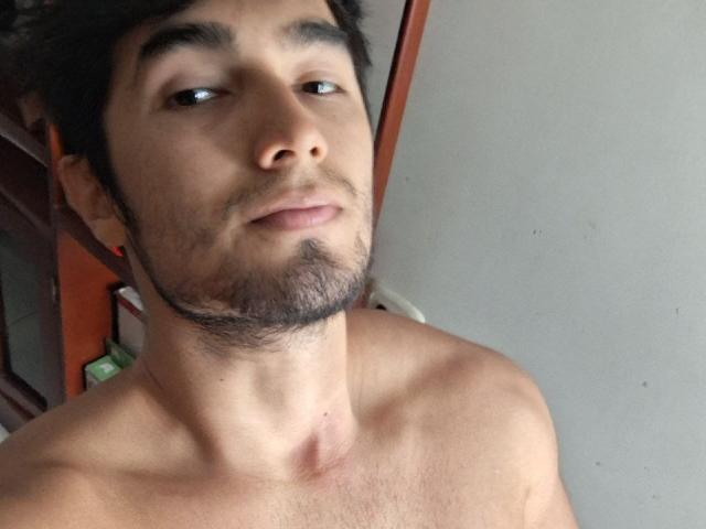 EliasX has a light brown skin tone, dark curly hair, a thin beard, and a neutral expression. He's shirtless with a visible neck and upper chest.